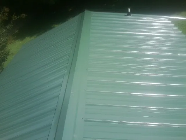 New green metal panels meeting at the ridge of a roof — Flat Roof Repair work by our crew in Stanfield
