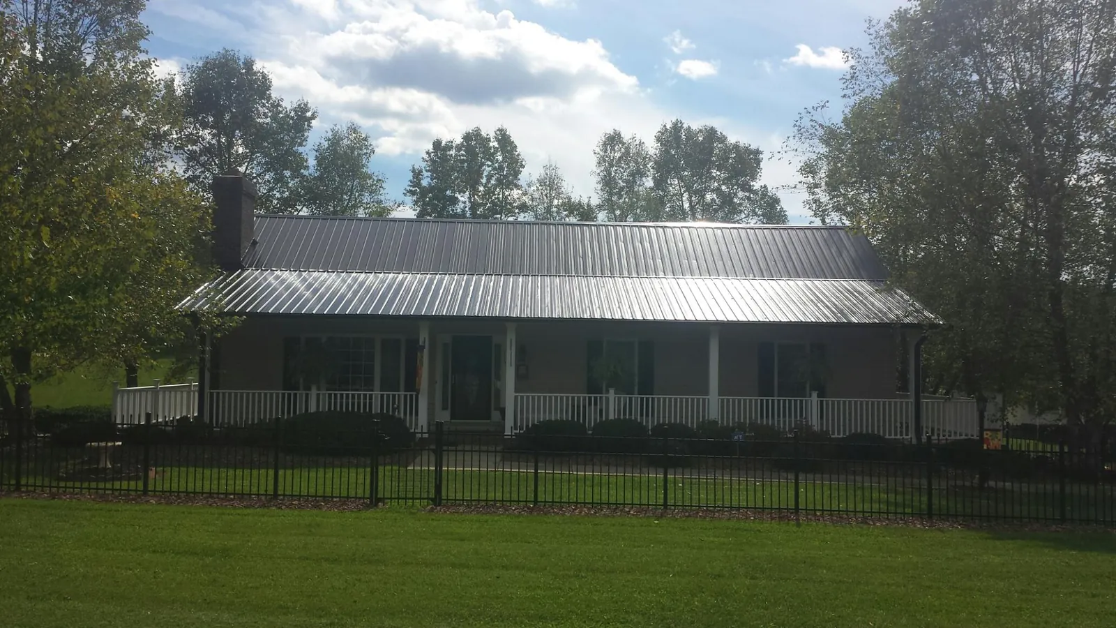Gray metal roof on a brick ranch with a full width front porch — Gutter Guard Installation work by our crew in Stanfield