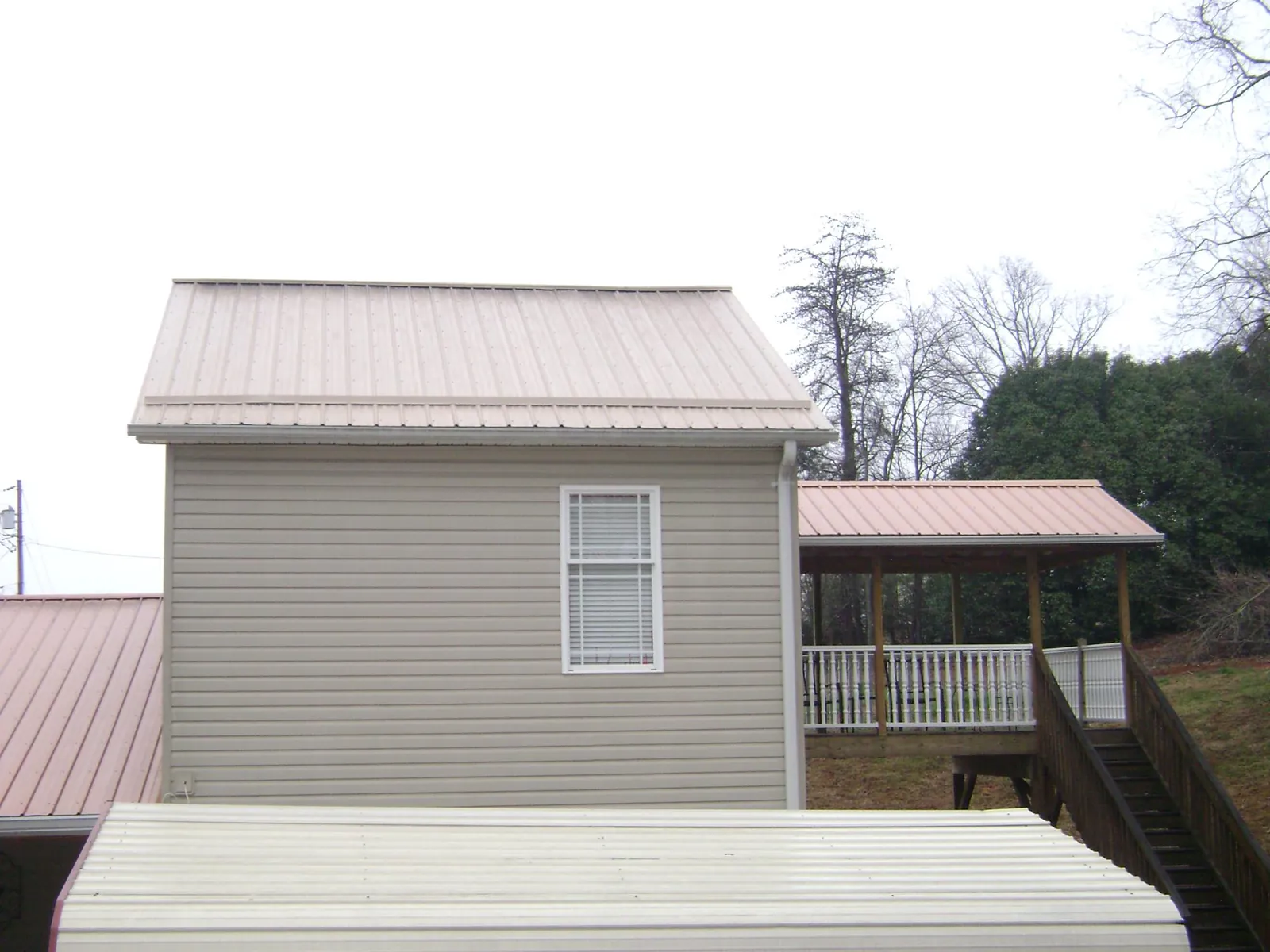Tan metal roofs on a two story addition and attached porch, from a Roof Replacement job in Stanfield